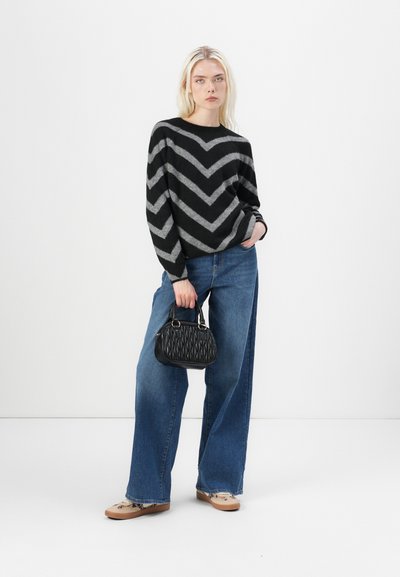 Suéter a rayas en blanco y negro, jeans de mezclilla azul de corte holgado, bolso texturizado negro y zapatos planos beige. Estética sencilla y moderna.