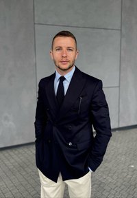 Mornarsko sako s dvostrukim kopčanjem i sjajnim gumbima, uparen s svijetloplavom košuljom i tamnom kravatom, uz krem hlače.