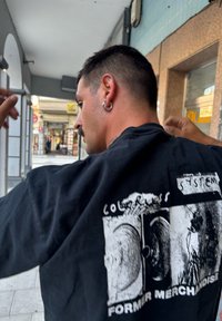 Zwarte katoenen t-shirt met een grafische print op de achterkant met twee afbeeldingen en de tekst "COLORLESS SYSTEM FORMER MERCHANDISE."