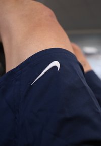 Los pantalones cortos azul marino presentan un logo de Nike bordado en blanco cerca del dobladillo, hechos de una tela texturizada con un acabado suave.