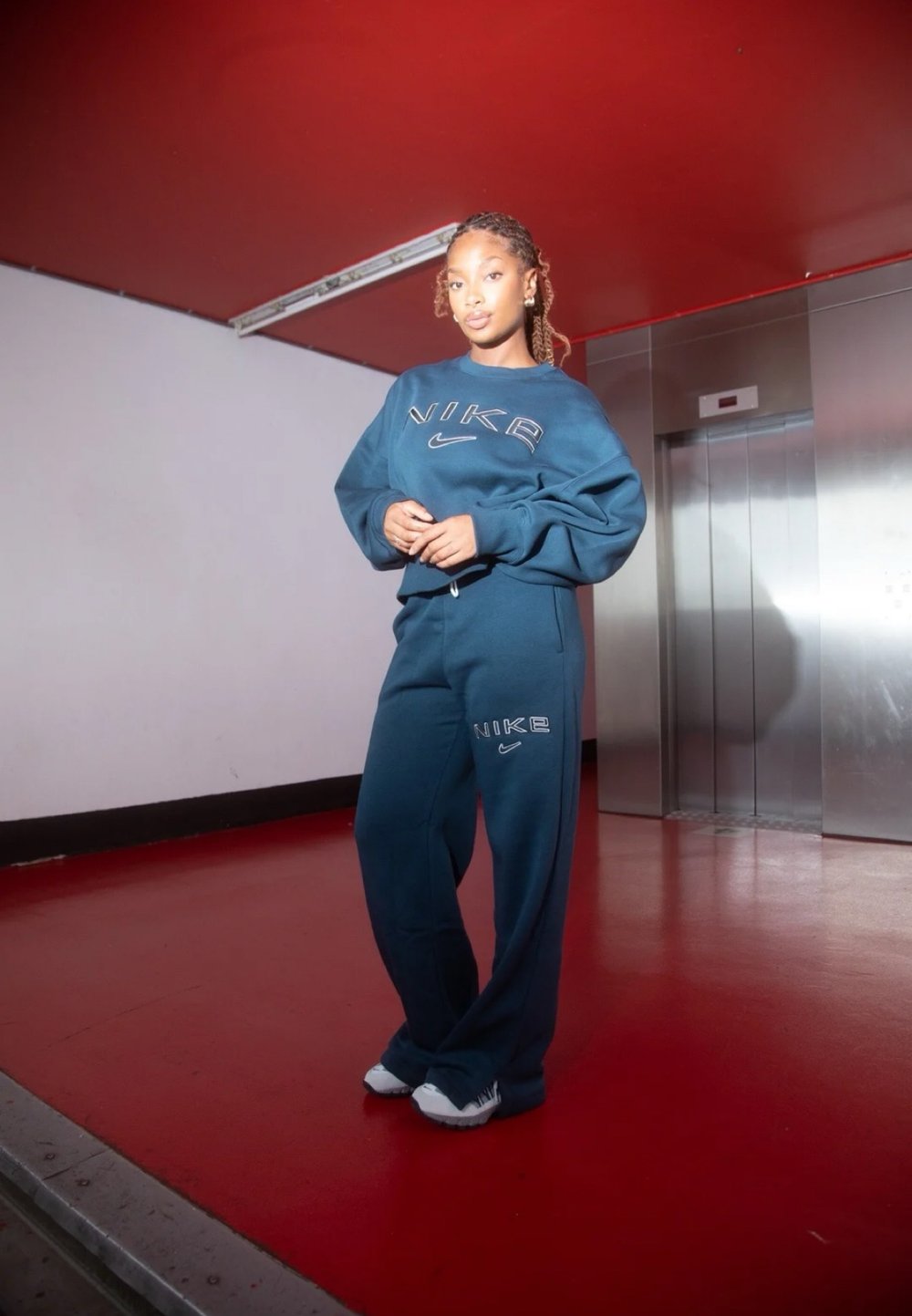Προπόνηση σε σκούρο μπλε χρώμα με τα αντίστοιχα παντελόνια φόρμας, διακοσμημένα με το κεντημένο λογότυπο "NIKE", χαρακτηριστικά με άνετη εφαρμογή και μαλακή υφή. Τα λευκά αθλητικά παπούτσια ολοκληρώνουν το ντύσιμο.