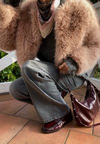 Ψεύτικο γούνινο ροζ μπουφάν, γκρι πουλόβερ, γκρι παντελόνι σε γραμμή καμπάνα, μπορντώ δερμάτινη τσάντα και ταιριαστά loafers. Το λουλουδένιο φουλάρι ολοκληρώνει την εμφάνιση.