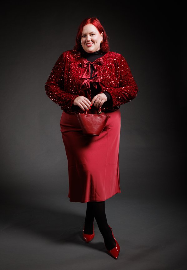 Piros flitteres dzseki masnival, piros szatén szoknya, fekete harisnya és piros lakk magassarkú. Egy kis piros kézitáska egészíti ki a szettet.