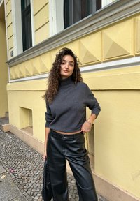 Hallhalline turtleneck-sviiter, millel on lühendatud disain, kombineeritud kõrge vöökoha ja laia säärega mustade nahkpükstega. Tekstuuriga kudum ja sile nahk.