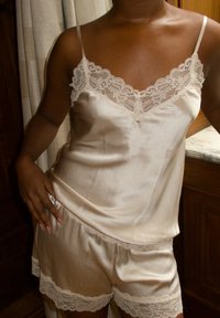 Satin Schlafanzug-Set aus zwei Teilen in sanftem Beige, bestehend aus einem ärmellosen Top mit Spitze und passenden Shorts mit elastischem Bund und Spitzenakzenten.