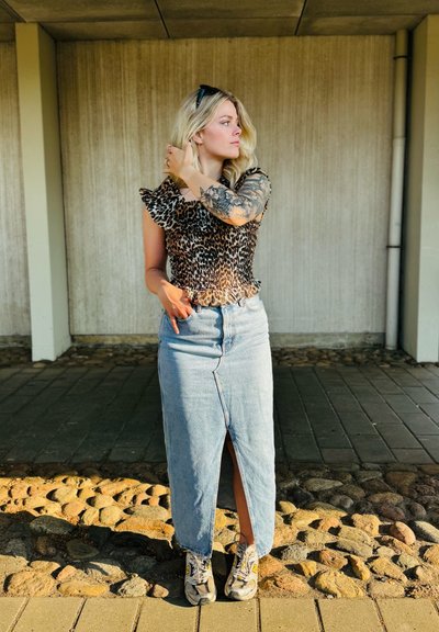 Top de estampado de leopardo con mangas acampanadas, combinado con una falda maxi de mezclilla clara con una abertura frontal. Llevado con zapatillas estampadas.