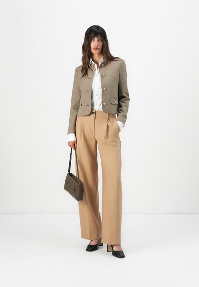 Chaqueta corta de cuadros marrones, blusa blanca, pantalones de pierna ancha en color beige, tacones negros, bolso gris con patrón en zigzag, texturas suaves.