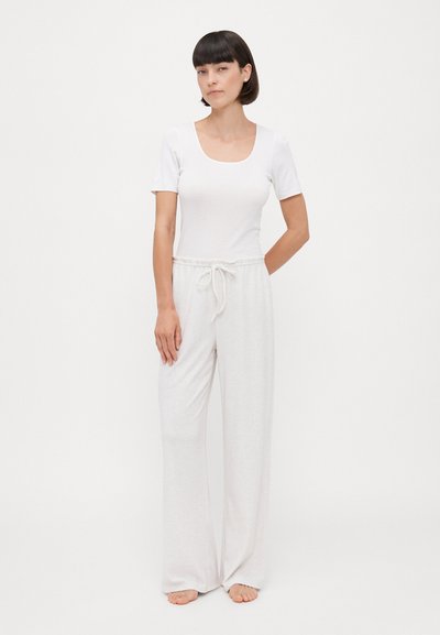 Camiseta blanca ajustada de manga corta y escote cuadrado, combinada con pantalones de pierna ancha en gris claro, con cordones y fabricados en una tela suave.