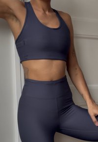 Námornícky modrý rebrovaný crop top a legíny s vysokým pásom, obe vyrobené z elastického materiálu, s bezšvovým dizajnom a priliehavým strihom.