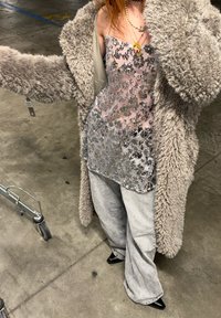 Débardeur à sequins argentés sous un manteau gris duveteux, associé à un jean large gris clair et des talons noirs à bout pointu.