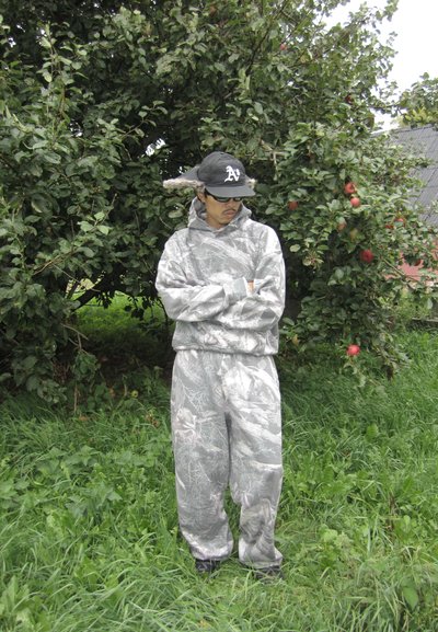 Sudadera y pantalones deportivos de camuflaje gris, con patrones detallados de hojas, corte holgado y textura suave, combinados con una gorra y gafas de sol.