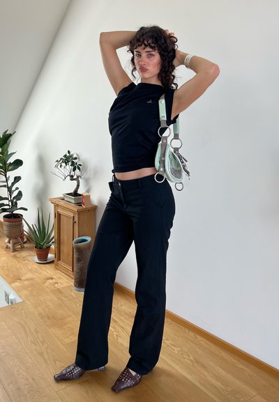 Camiseta negra ajustada, pantalones de pierna ancha negros y tacones marrones con estampado. Los accesorios incluyen un bolso verde menta con herrajes plateados.
