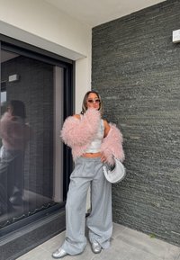 Pink fluffy outerwear, silver shiny top, grey wide-leg trousers, and metallic shoes, accessorised with a silver handbag and round sunglasses.