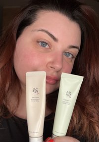 Två kosmetiktuber hålls i en hand: en krämfärgad tub med en flipplock märkt "Revive Eye Serum" och en grön tub märkt "Light On Serum."