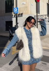 Jeans obleka z gumbom spredaj, dolgimi rokavi in belim umetnim krznom. Vključuje rjavo torbico z vzorcem in sončna očala.