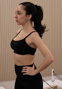 Sort sports-bh med tynde stropper og et cropped design, kombineret med sorte leggings med høj talje. Glat stof og kropsnær silhuet.