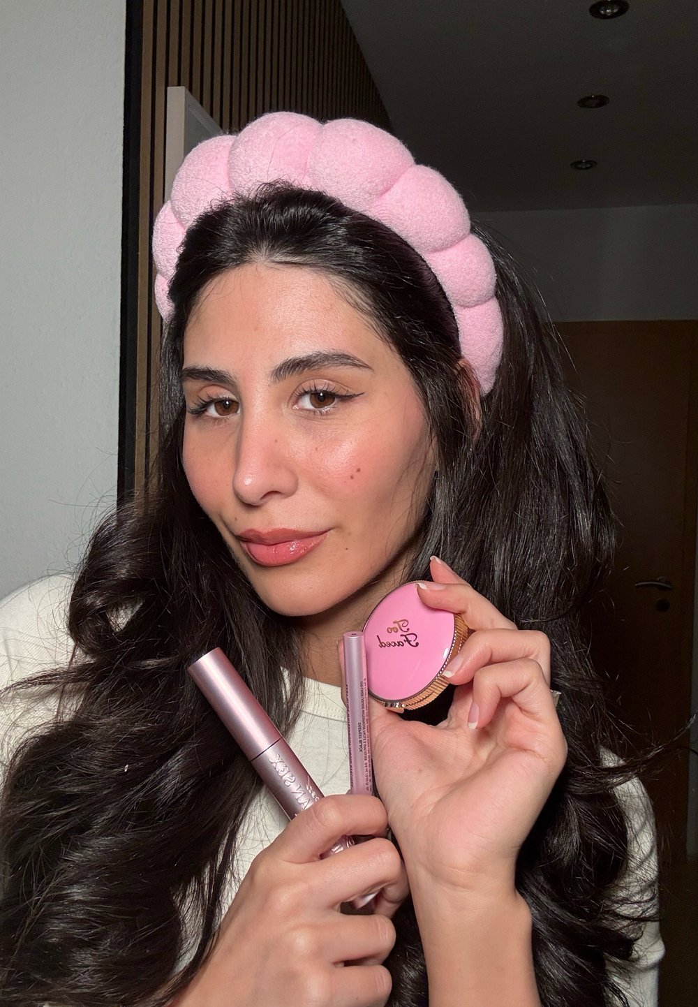 Roze, zachte haarband met ronde vormen; houdt een roze mascara, een lipproduct en een compact met "Sweet" erop gegraveerd; gladde texturen.
