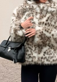 Faux fur coat with brown and white spotted pattern, paired with a structured black leather handbag featuring a silver clasp and handles.