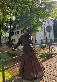 Pruun kihiline riietus, millel on istuv ülemine osa ja voolav seelik, valmistatud kergest kangast. Üksik hijab sobib komplekti.