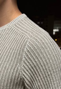Light grey ribbed knit jumper featuring a crew neckline and subtle texture contrast at the seams. Close-up emphasises stitch details.