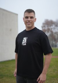 T-shirt noir à manches courtes avec un motif imprimé central représentant des vagues. Fabriqué en coton, il présente une coupe décontractée et un col rond.
