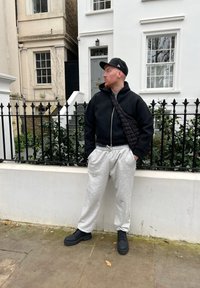 Monokromt outfit med en sort zip-up hættetrøje, grå sweatpants og sorte snørebåndsstøvler. En struktureret crossbody-taske bæres diagonalt.