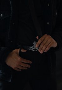 Μαύρη δερμάτινη ζώνη με υφή κροκόδειλου. Διαθέτει ασημένια μεταλλική αγκράφα σε σχήμα πλοίου, διακοσμημένη με μικρά καρφιά.