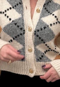 Πλεκτό cardigan με σχέδιο διαμαντιού σε μπεζ, γκρι και πορτοκαλί. Έχει χρυσά κουμπιά και ριμπ μανσέτες και στρίφωμα.