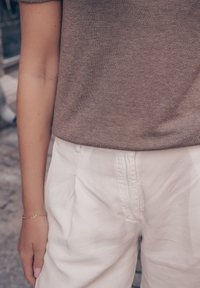 Brun stickad topp i kombination med ljusgrå linnbyxor. Outfiten har en avslappnad passform med subtil textur och minimalistisk design.