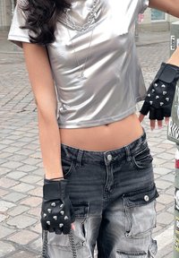 Ασημένιο κοντομάνικο γυαλιστερό crop top; μαύρα γάντια χωρίς δάχτυλα με ασημένιες μελένιες; φθαρμένα μαύρα και γκρίζα cargo παντελόνια με τσέπες.