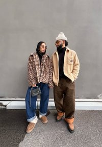 Ζακέτα από ψεύτικη γούνα με λεοπάρ μοτίβο, μαύρο ζιβάγκο, μπλε φαρδιά τζιν παντελόνια με παπούτσια με γούνα στο εσωτερικό; μπεζ φλις ζακέτα, καρό παντελόνια, σκουφάκι.