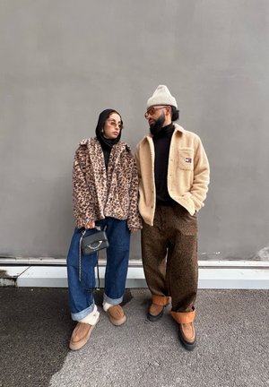 Leopard print faux fur jacket, black turtleneck, blue wide-leg jeans with fur-lined shoes; beige fleece jacket, patterned pants, beanie.