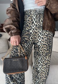 Džínsy s leopardím vzorom a vysokým pásom, hnedá kožená bomber bunda a čierna kabelka Michael Kors so zlatým reťazovým popruhom.