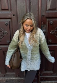 Φουντωτό κανελάκι σε πράσινο και γαλάζιο βαθμιδωτό χρώμα, με μακριά μανίκια, κουμπιά μπροστά και άνετη γραμμή, συνδυασμένο με μια καφέ τσάντα.