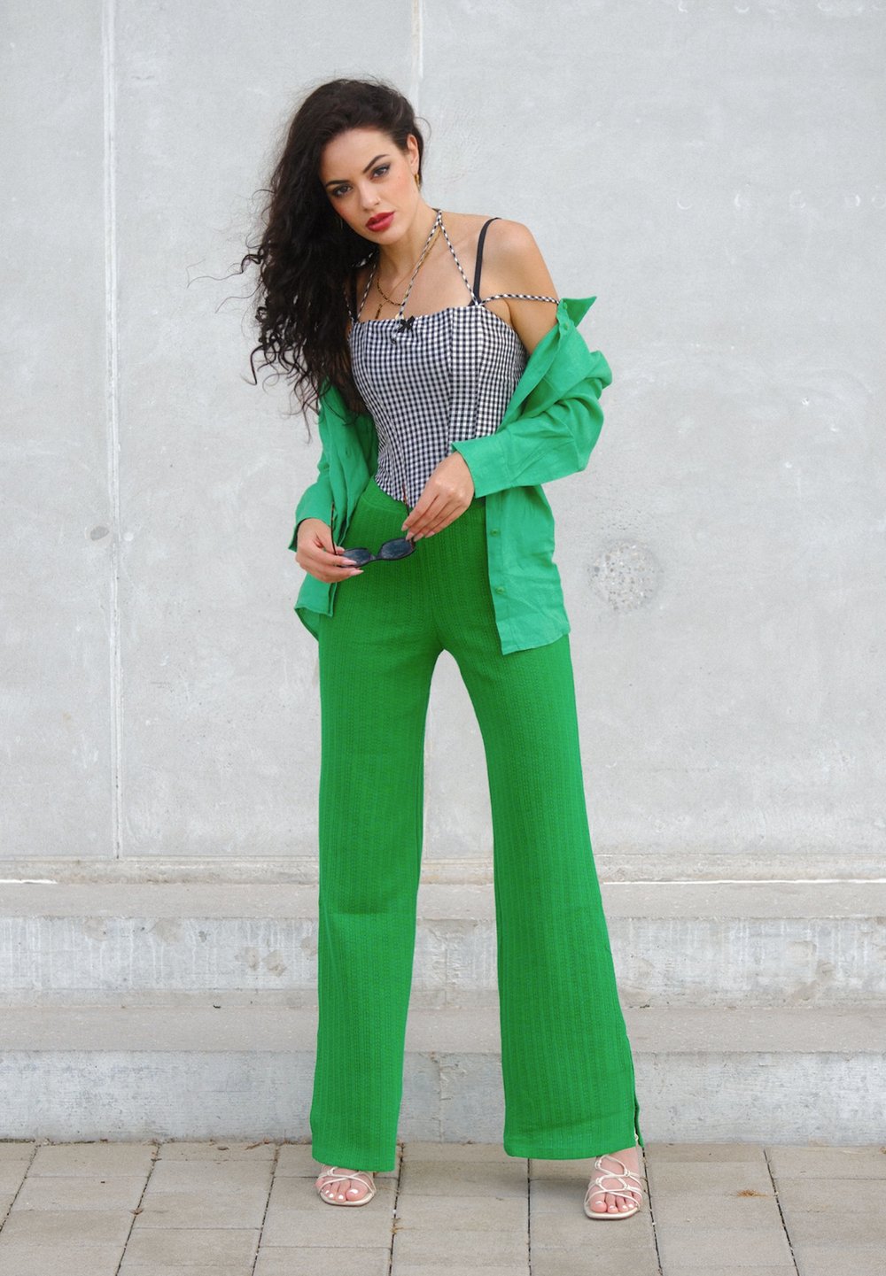 Črno-bela gingham brezrokavnik se ujema z svetlo zelenimi, teksturiranimi širokimi hlačami. Na vrhu je oblečena ohlapna zelena srajca.