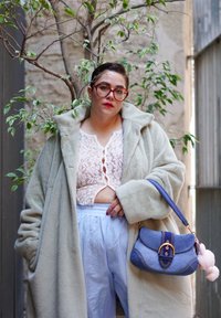 Casaco sobre leve e fofinho em cinza claro; top cropped de renda branca; calças largas azuis; mala de jeans com ferragens douradas; detalhe de pompom rosa.