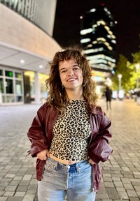 Læderjakke i bordeaux over en leopardmønstret crop top, parret med lyseblå slidte jeans udsmykket med sølvdetaljer. Natsituation.