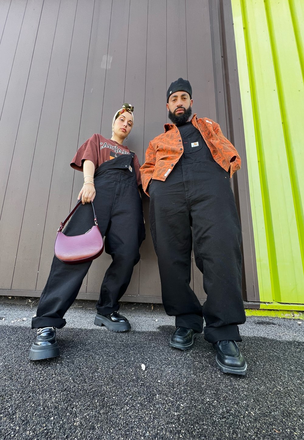 Μαύρες σαλοπέτες φορεμένες πάνω από ένα καφέ γραφικό μπλουζάκι, συνδυασμένες με ένα εμπριμέ πορτοκαλί μπουφάν. Τα αξεσουάρ περιλαμβάνουν μια μωβ τσάντα και μαύρα παπούτσια με πλατφόρμα.