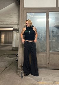 Top scurt negru fără mâneci, cu glugă, detalii verzi; blugi negri din denim cu picioare largi; purtat cu pantofi negri; accente de bijuterii din argint.
