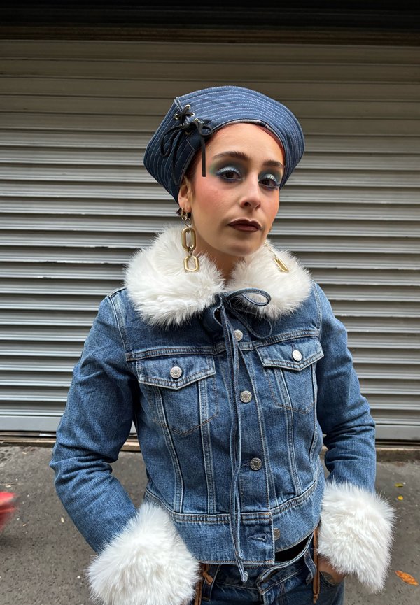 Spijkerjasje met een nepbonten kraag en manchetten, voorzien van een striksluiting, twee borstzakken en een blauw-wit gestreepte hoed.