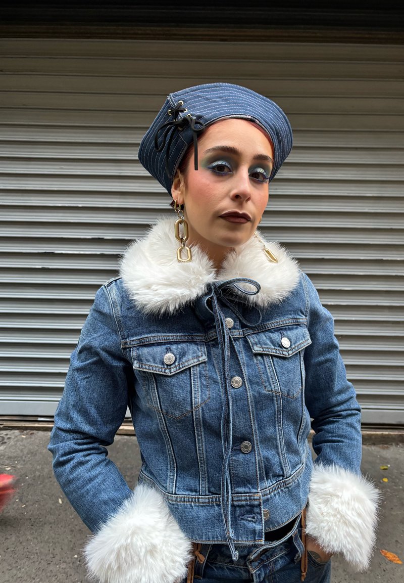 Veste en jean avec un col et des poignets en fausse fourrure, dotée d'une fermeture à nouer, de deux poches poitrine, et d'un chapeau rayé bleu et blanc.