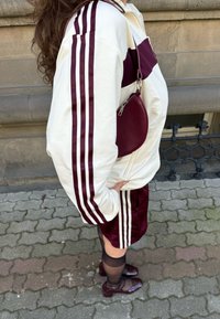 Krēmkrāsas josta jaka ar sarkanu joslu, savienota ar sarkanu zīda šortiem. Atbilstoša sarkana ādas apaļā soma un brūnas lakādas kurpes.