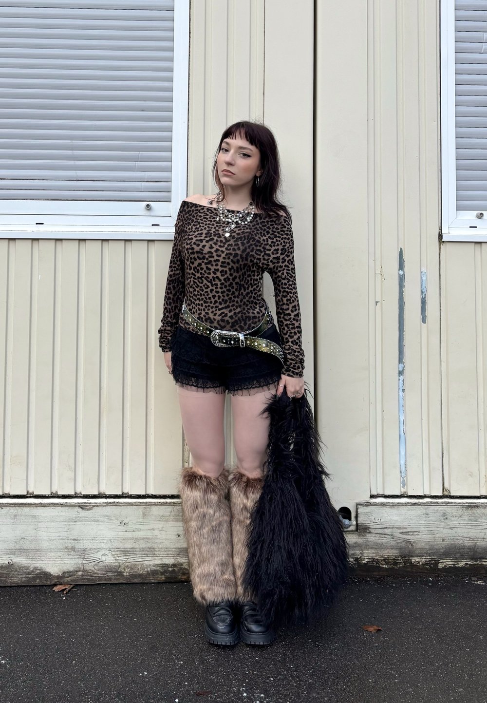 Top z dolgimi rokavi v leopardjem vzorcu, črne čipkaste kratke hlače, umetne krznene nogavice in črne platform čevlje. Dodatki vključujejo debelo pas in ogrlico.