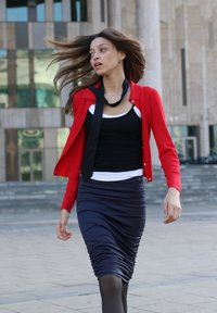 Rød ribbet cardigan over en svart tank top, parem med en svart rynket skjørt som fremhever tekstur og en tettsittende fasong. Glatt, flytende hår.