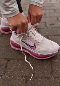 Nike'i jooksujalatsid heleroosas võrgus, lillaka Swooshiga. Omavad polsterdatud tallaga, mis on roosaka gradientiga ja valgete lukkudega.