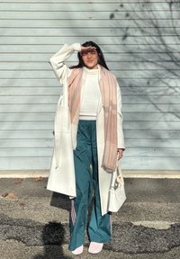 Vit lång kappa, rosa randig halsduk, vit topp, teal träningsbyxor med rosa detaljer och blekrosa skor. Accessoar: liten vit handväska.