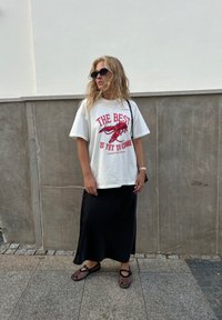 Valge ülikerge t-särk punaste graafiliste tähtede ja homaarimustriga, koos musta satiinse maksi-seeliku ja mustade võrkkingadega.