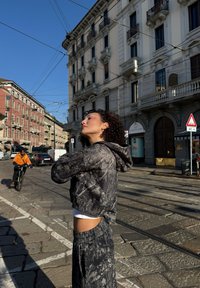 Harmaa kuvioitu, lyhyt huppari ja siihen sopivat collegehousut, joissa on teksturoitu kuosi, huppu ja joustava vyötärö, käytetty kaupunkimaisemassa.