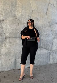 Crna bezrukava bluza, skraćene crne hlače i crni sako. Nosila je crnu tašnu i nosila životinjski uzorak sandale na petu. Pozadina je siva teksturirana zid.