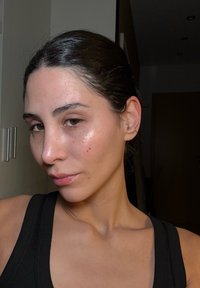 Profil einer Person mit langen dunklen Haaren. Die Haut hat einen leichten Glanz mit sichtbaren Sommersprossen. Trägt ein schwarzes Tanktop. Neutraler Hintergrund.